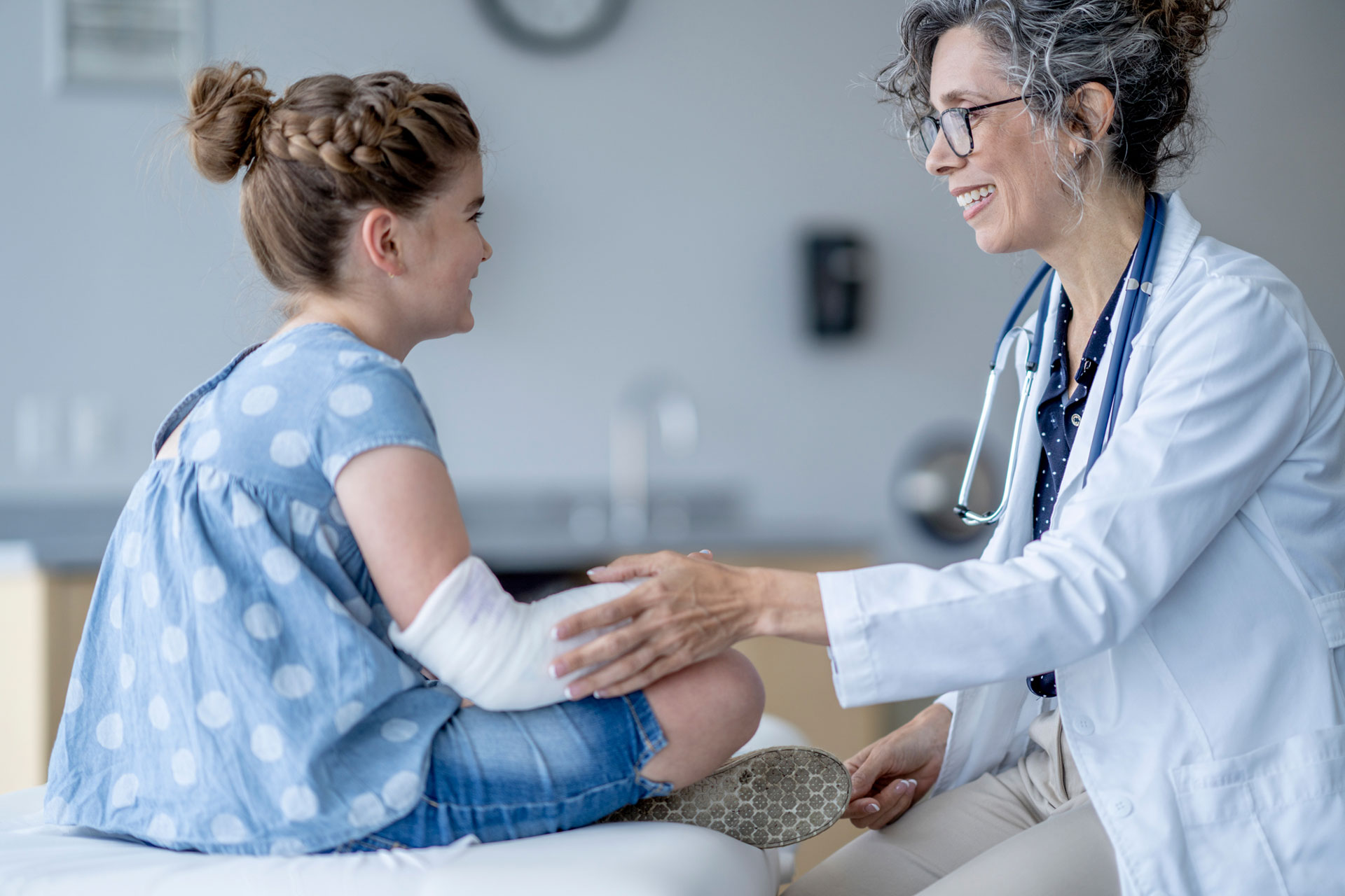 Doctor checking girl with a broken arm