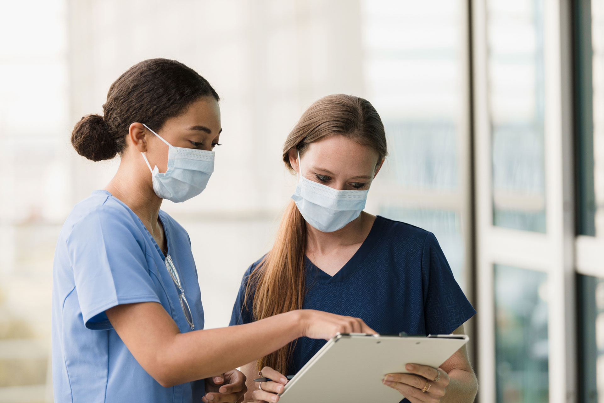 Two female surgeons discuss a patient chart