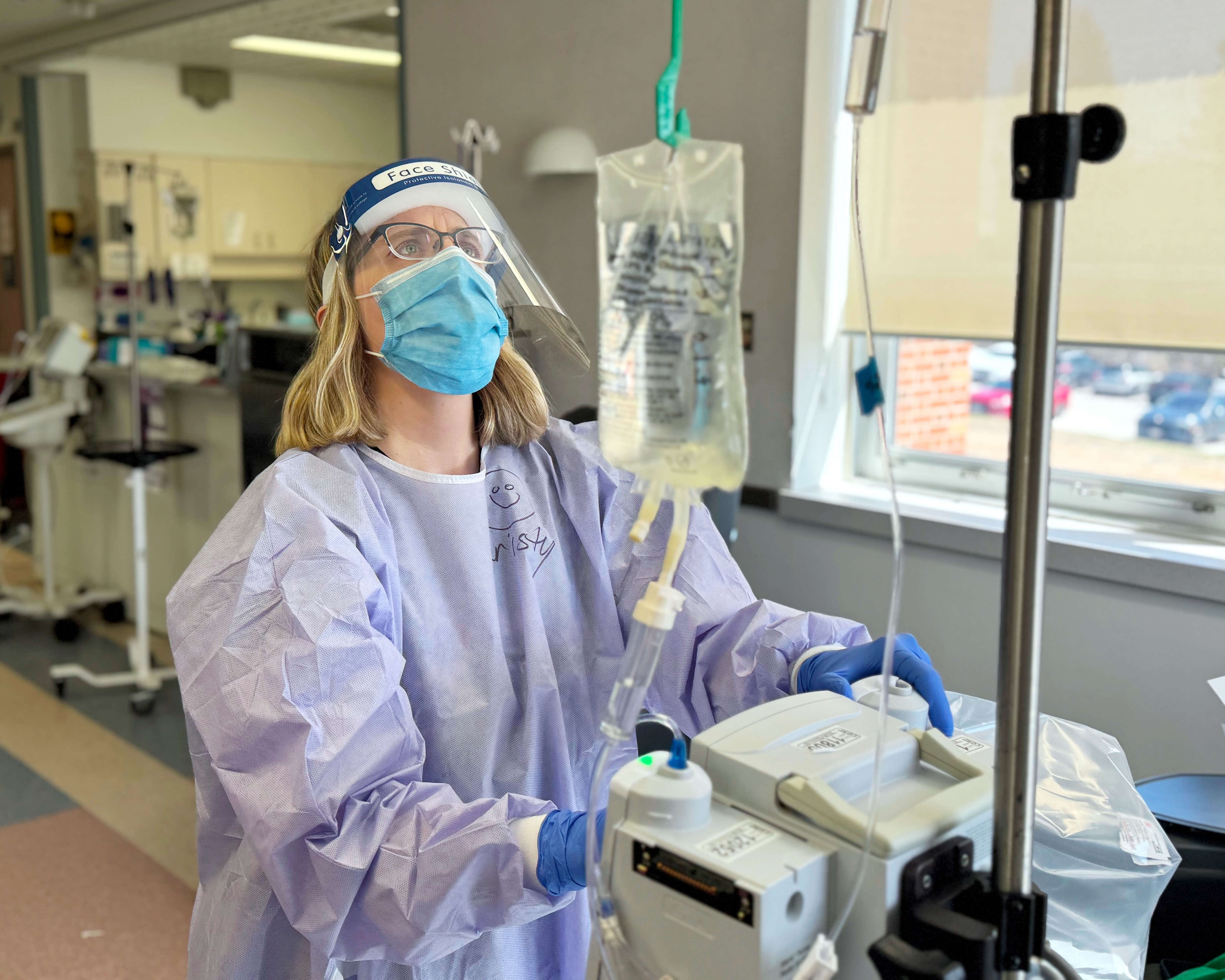 Kristy hangs up a treatment bag for a patient visiting the Medical Day Care for cancer treatment
